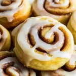 Delicious pie crust cinnamon rolls drizzled with icing on a white plate.