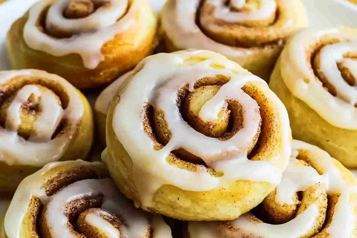 Delicious pie crust cinnamon rolls drizzled with icing on a white plate.